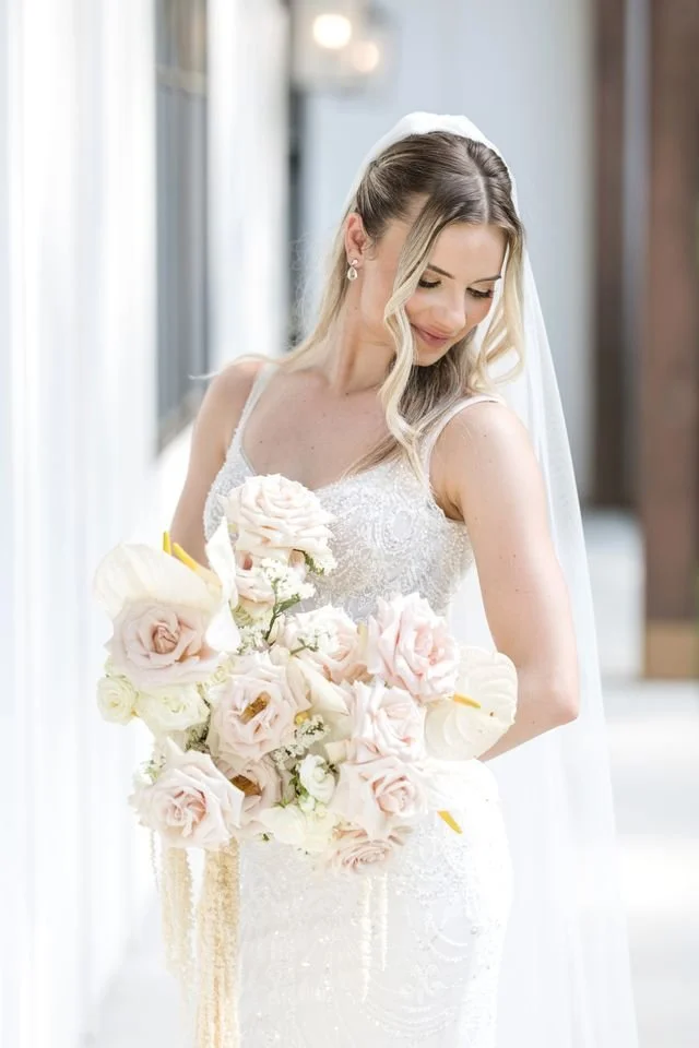 Bride holding a romantic blush and white bridal bouquet with roses and orchids for a luxury wedding. New Jersey Florist.