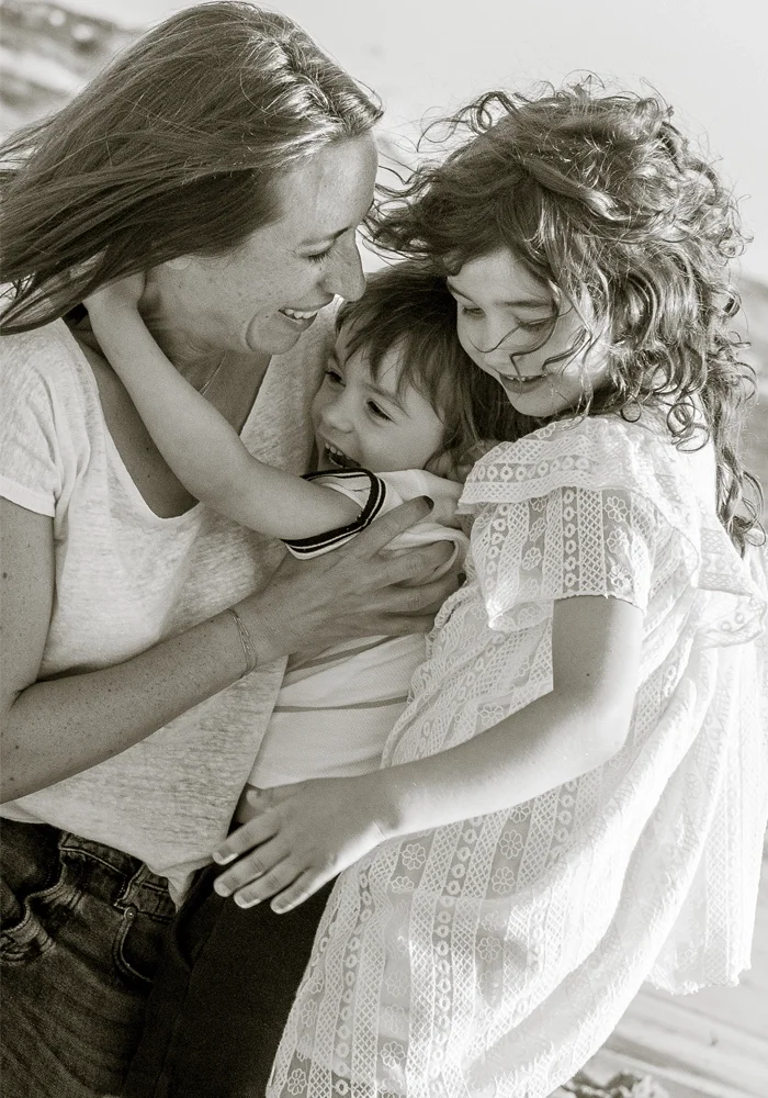 Mum cuddling her young children and laughing