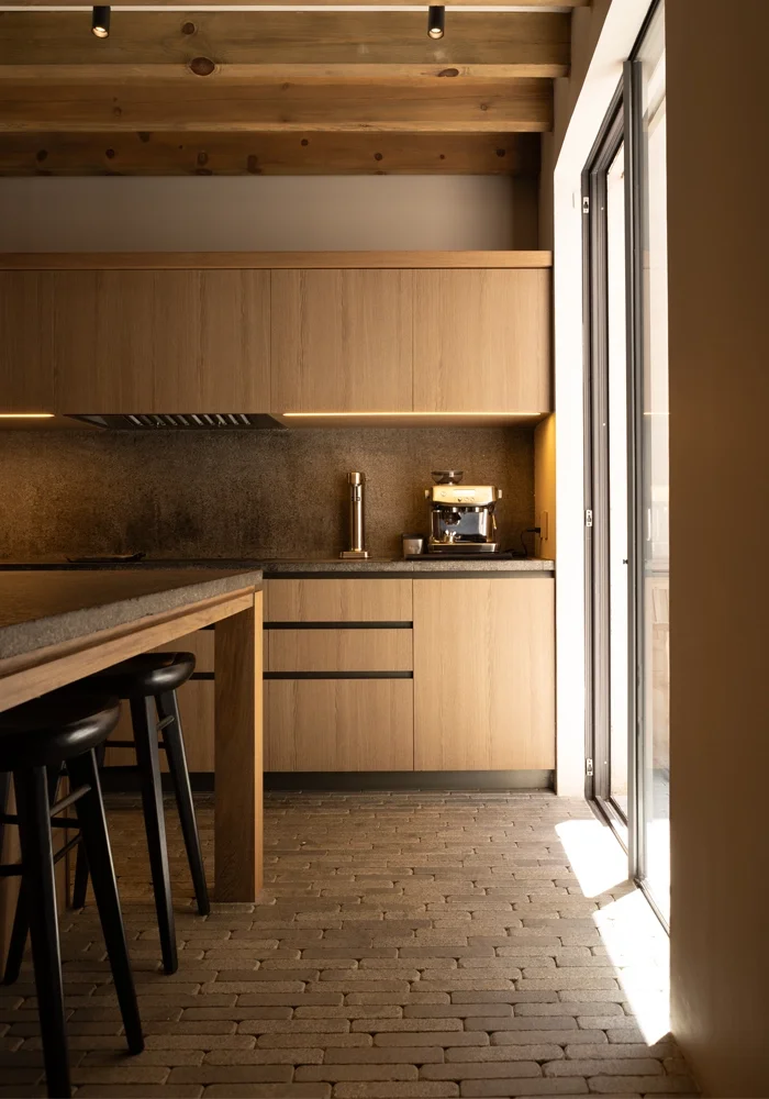 hotographie immobilière d’une villa contemporaine à Arcachon avec une cuisine minimaliste en bois massif et sol en pierre