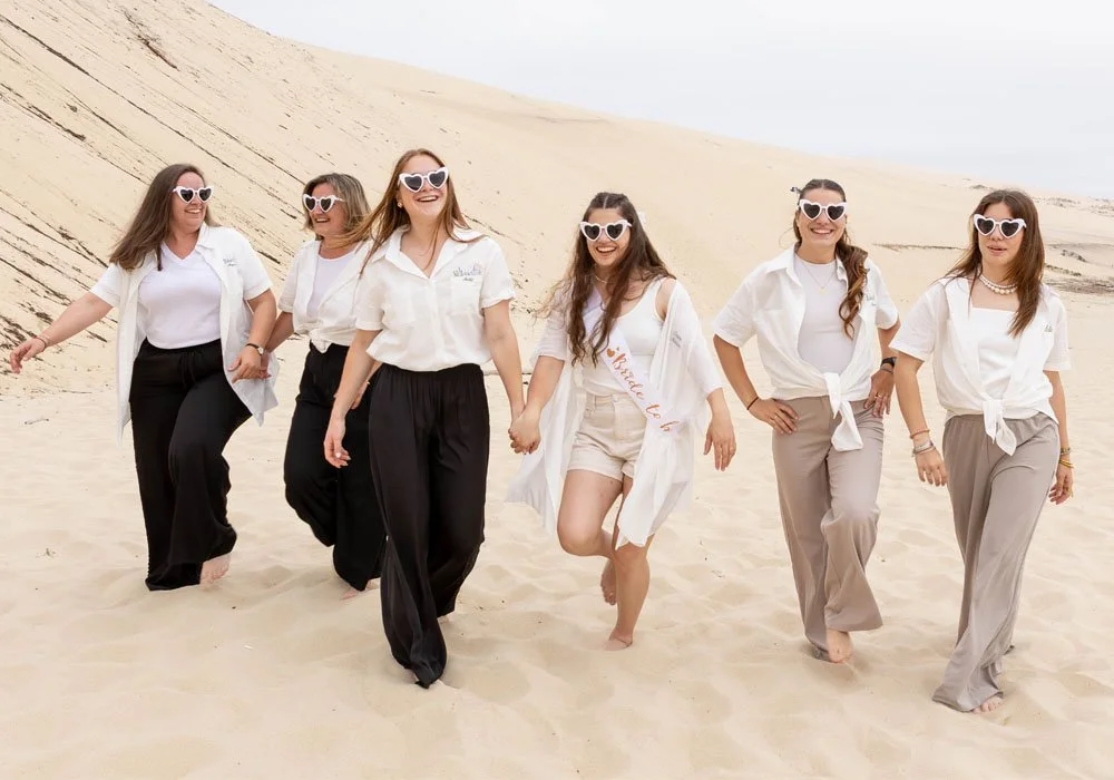 Amies marchant dans le sable pendant une séance photo EVJF à Pyla-sur-Mer