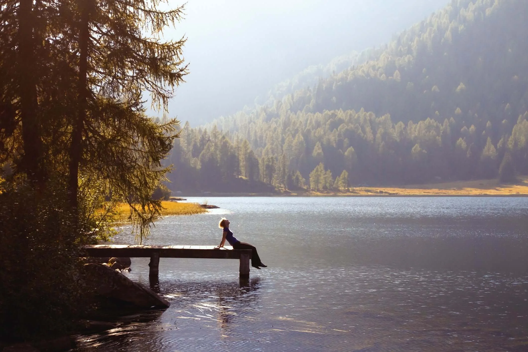 Person sitting by a lake reflecting, representing how to treat chronic pain.