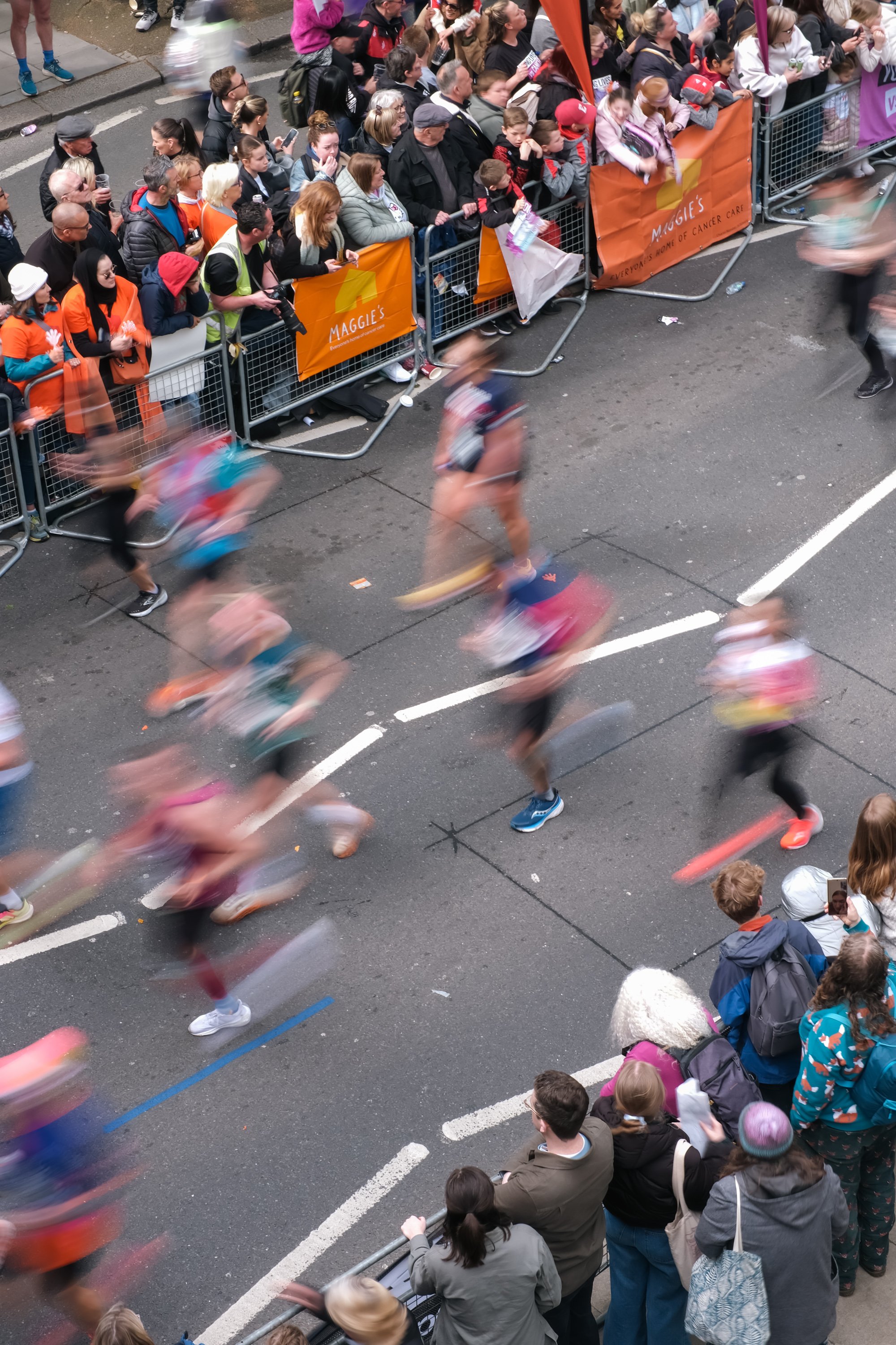 Group of marathon participants making their way through the streets of London with cheering crowds.