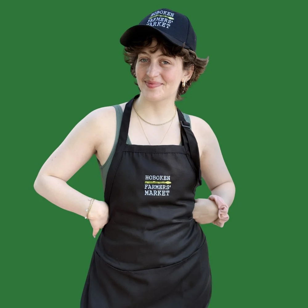 Woman wearing a black apron and black cap, both with the Hoboken Farmers' Market logo