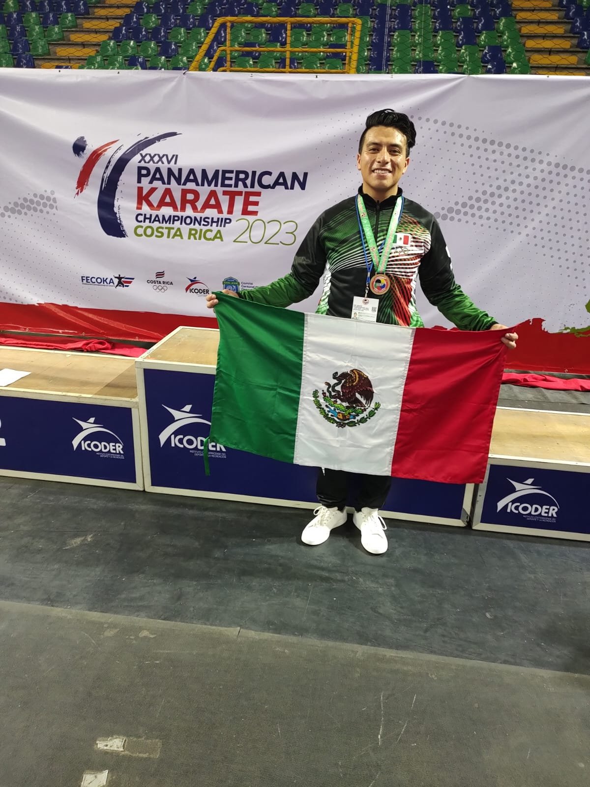 Persona con uniforme de México sosteniendo una bandera mexicana en el Campeonato Panamericano de Karate 2023 en Costa Rica.