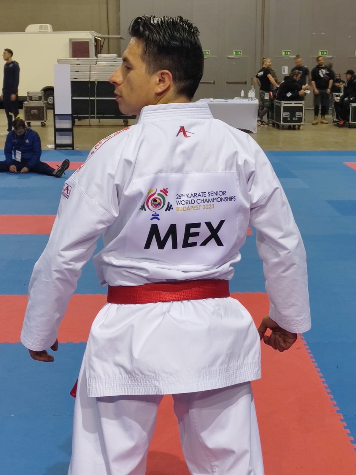 Practicante de karate en uniforme con cinturón rojo en un torneo, con "26th Karate Senior World Championships Budapest 2023 MEX" en la espalda.