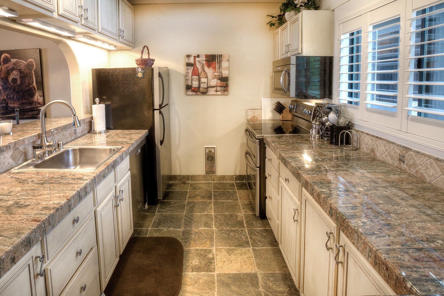 unit 47 kitchen with off-white cabinets, taupe granite counter, and white wide-slat shutters