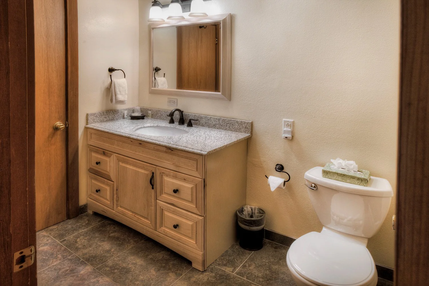 unit 23 bathroom with rustic wooden cabinet with granite top and white fixtures