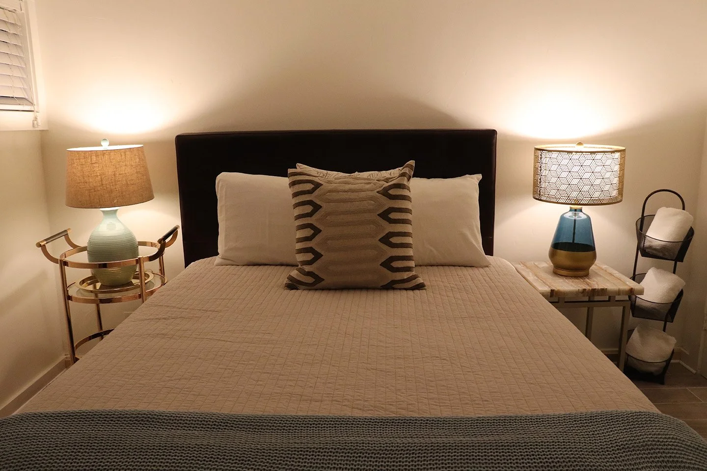 unit 18 bedroom  showing queen bed, with wooden bedframe, coverlet, decorative pillows, and bedside lamps