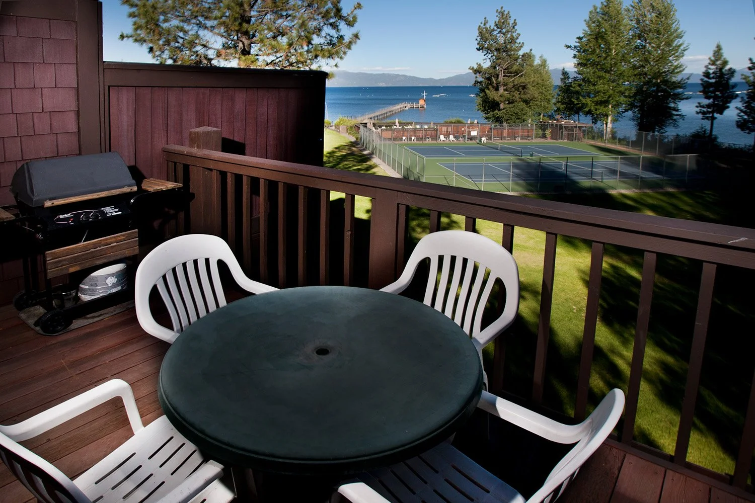 unit 5 back deck with table, white plstic chairs and view of tennis courts