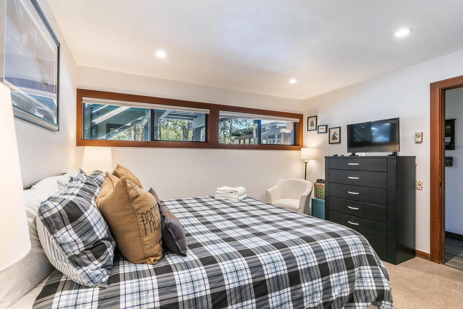 unit 3 bedroom with king-size bed with plaid bedspread includes view of chest of drawers with TV on top