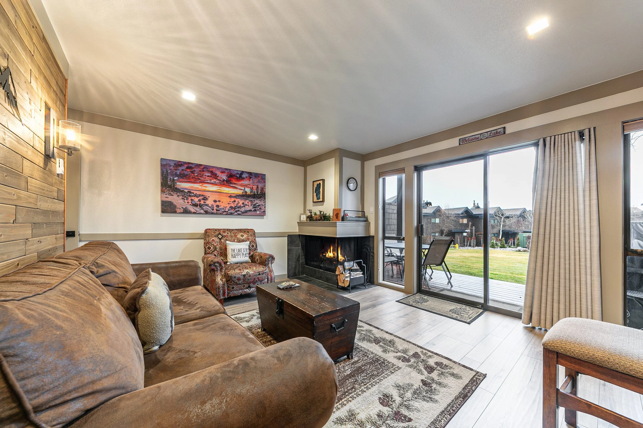 unit 17 living room with leather couch and fireplace. shows view out glass doors.