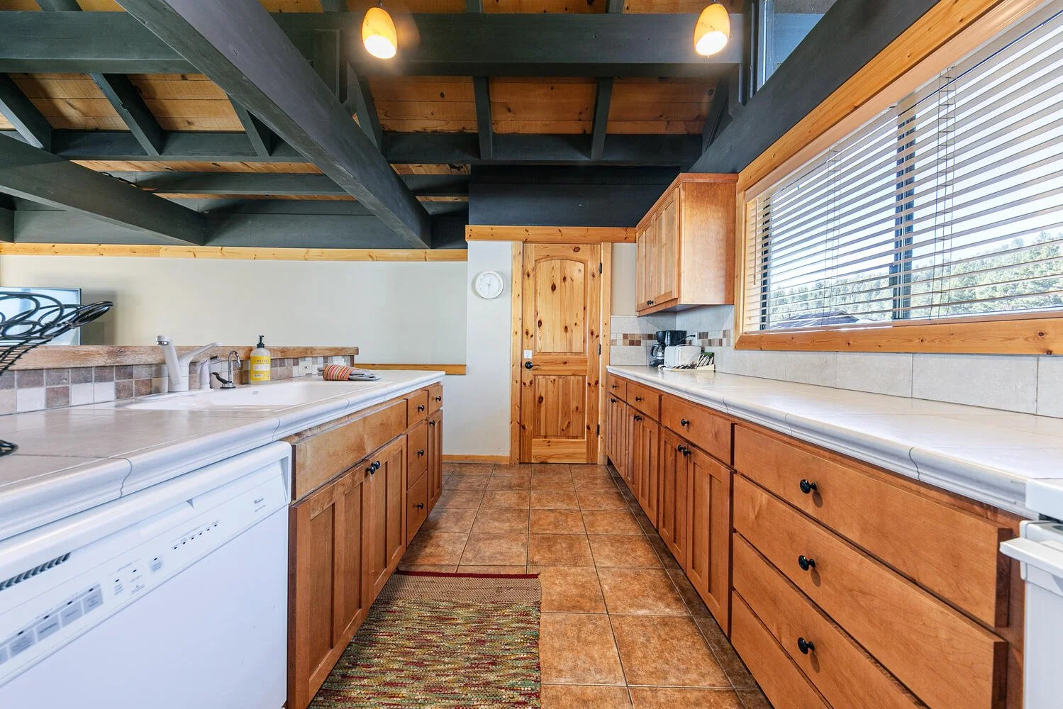 unit 7 kitchen with white tile countertops, pine cabinets, white appliances