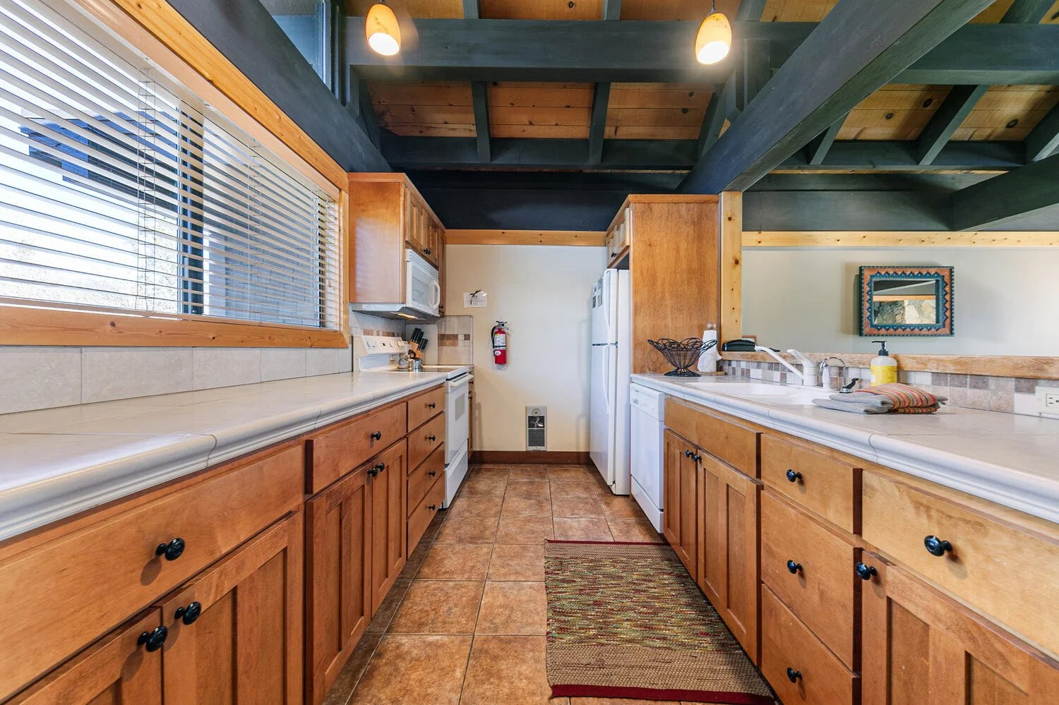 unit 7 kitchen with white tile countertops, pine cabinets, white appliances