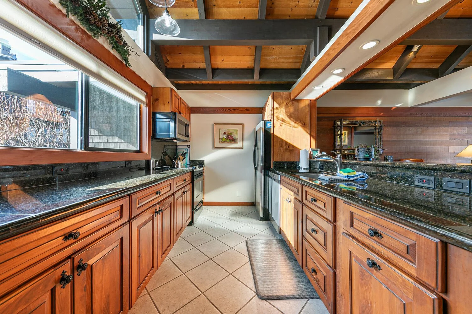 unit 42 kitchen showing tile floor, wood cabinets and dark granite countertop