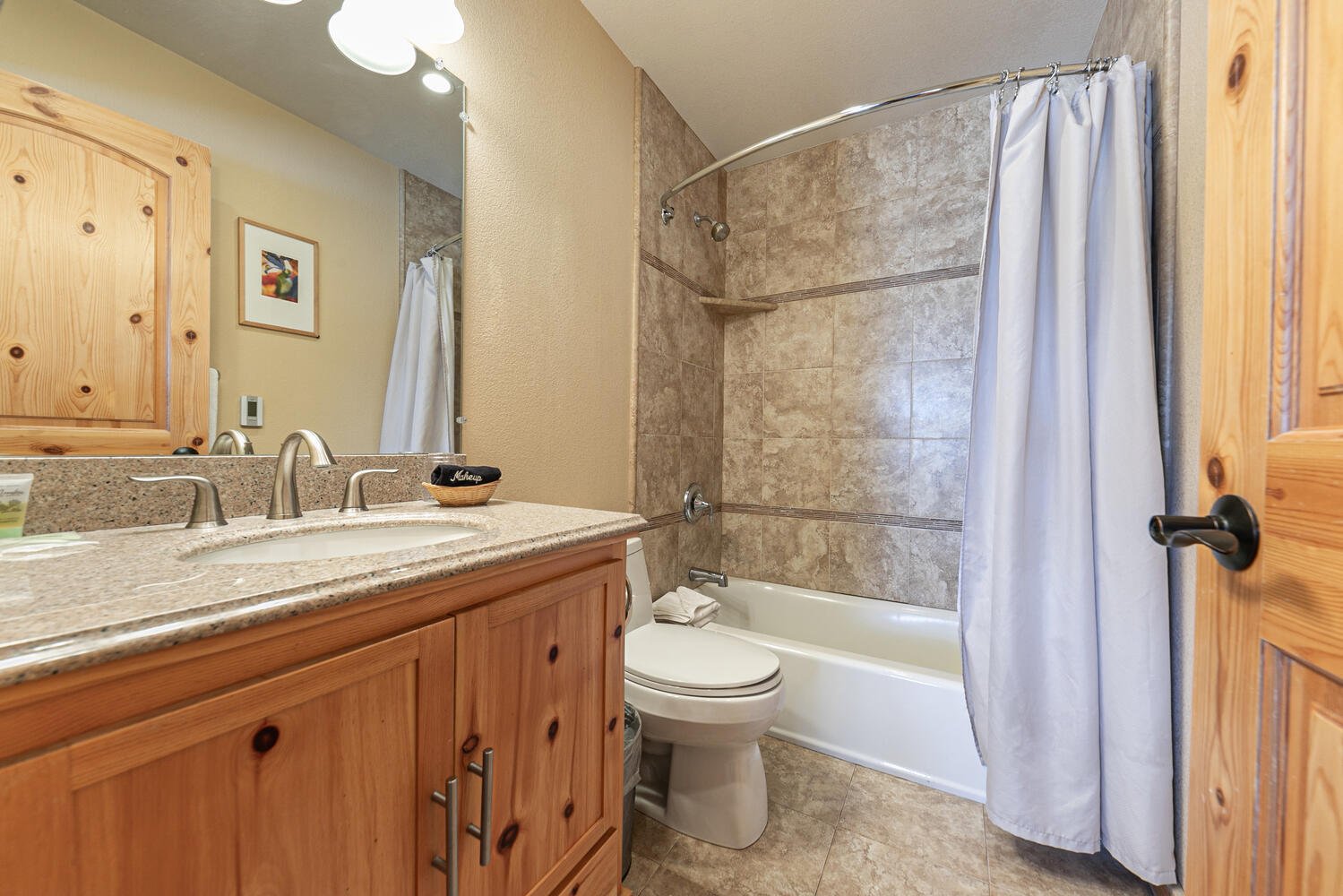 unit 7 main bathroom with pine cabinets and light countertops, shower with curtain