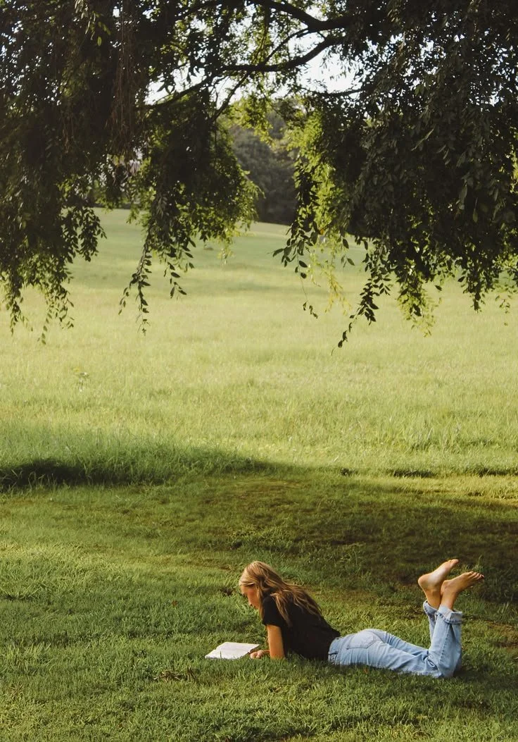 A woman reading a book on a field, getting herself informed in a mindful, intentional way.