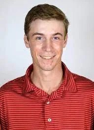 A young man with short light brown hair, smiling, wearing a red and white striped polo shirt.