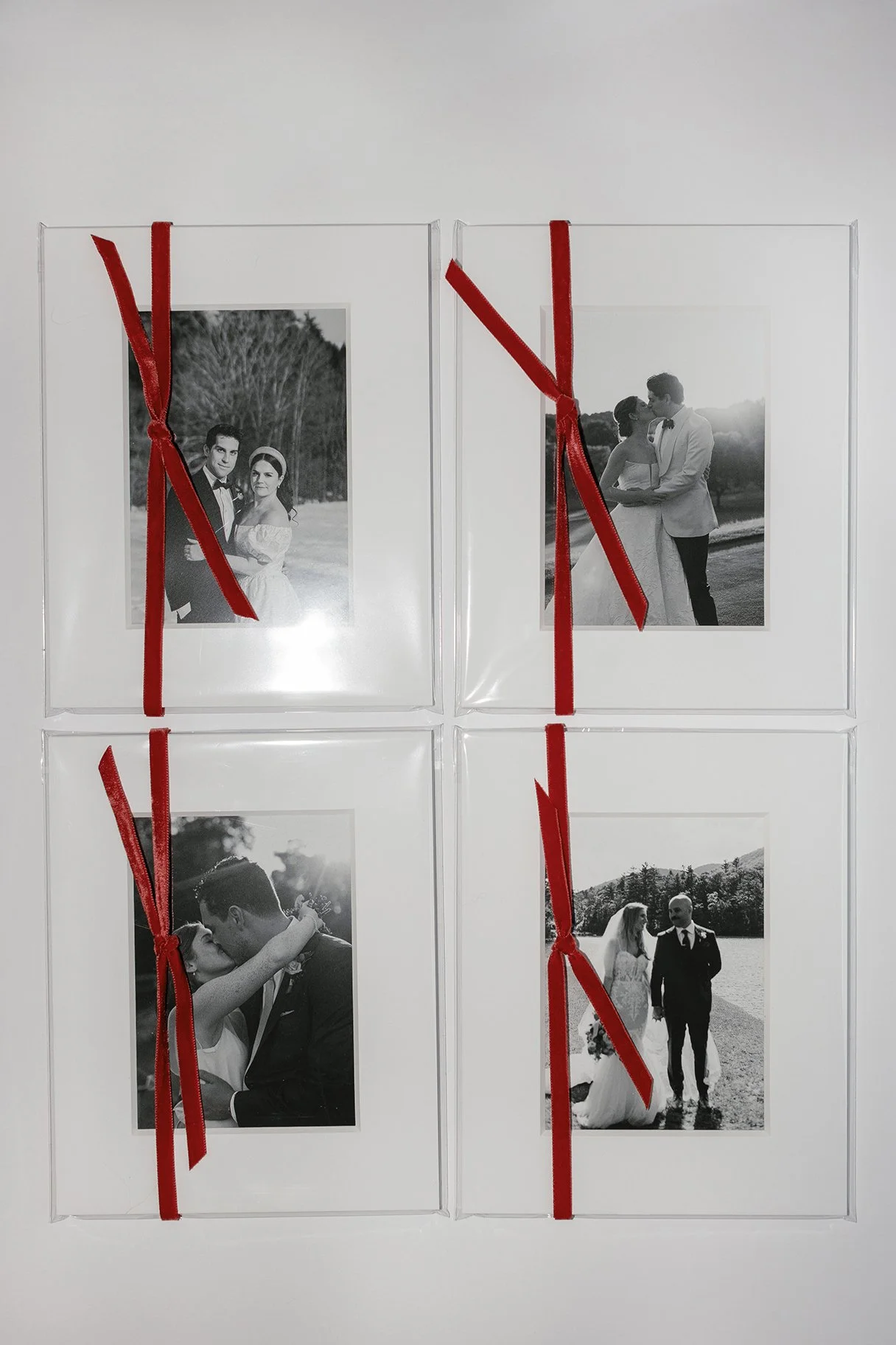 Four black and white wedding photos framed and wrapped with red ribbons.