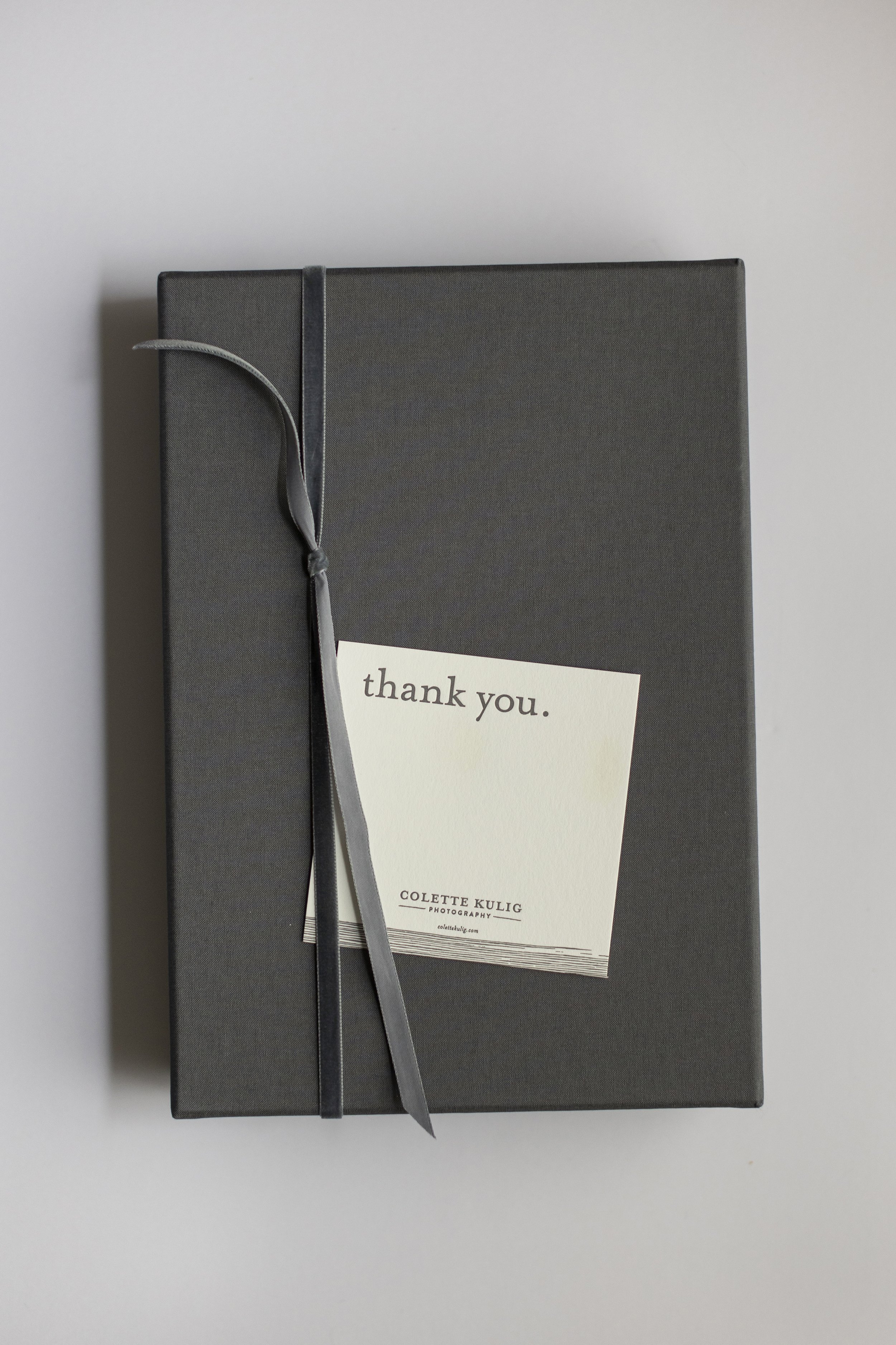 Gray gift box with a gray ribbon and a "thank you" card on top.