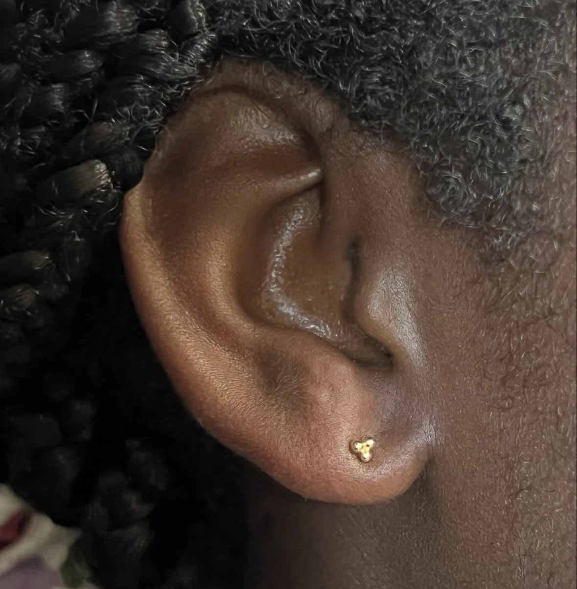 Close-up of a person's ear with small gold earrings.