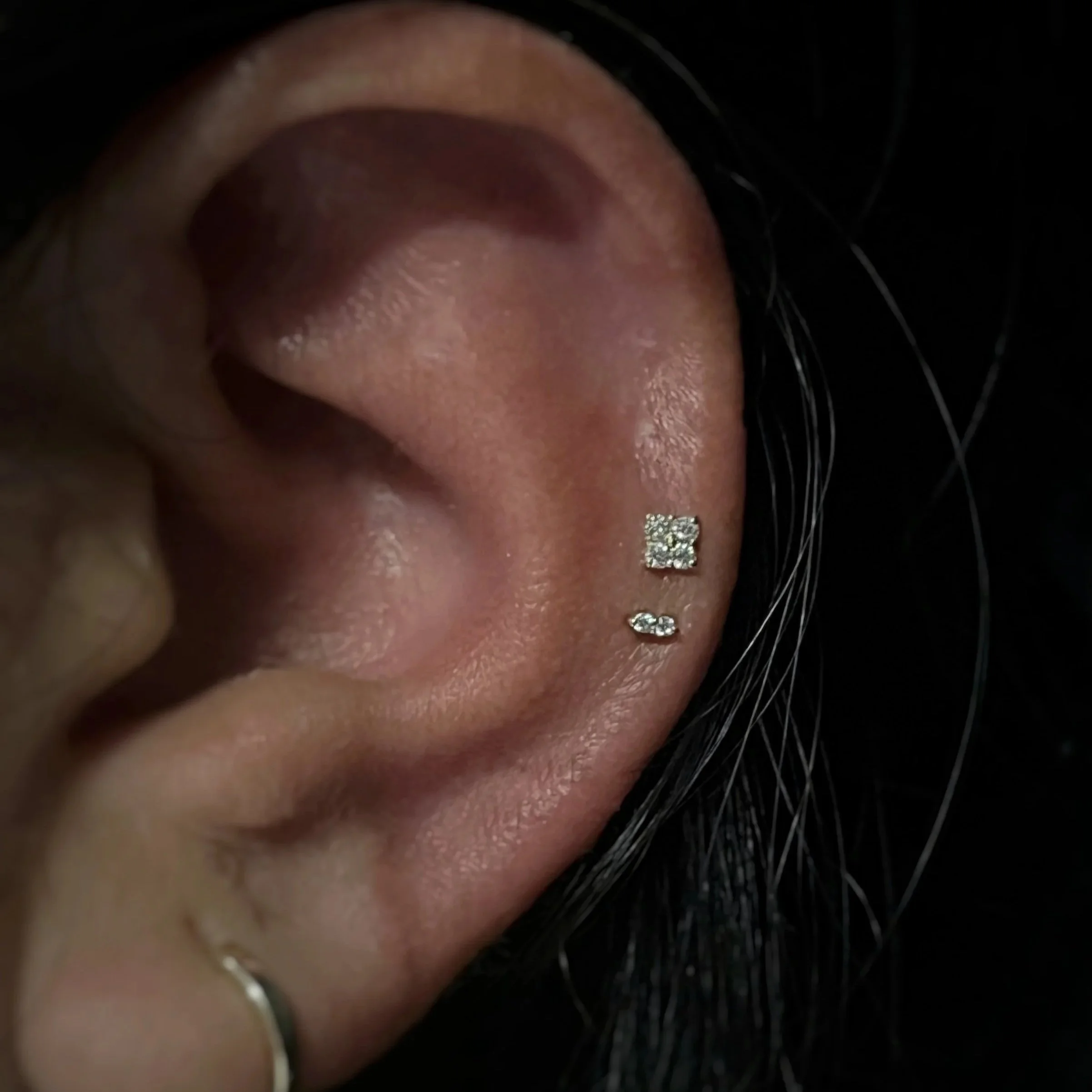 Close-up of a person's ear with two mid helox piercings