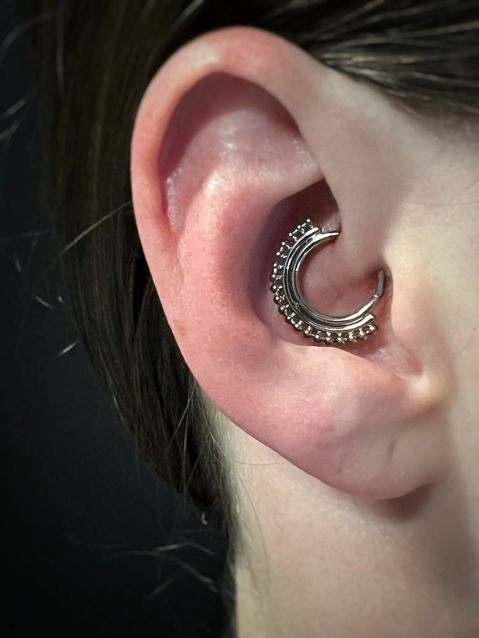 Close-up image of a person's ear with a decorative hoop earring that has beaded accents.