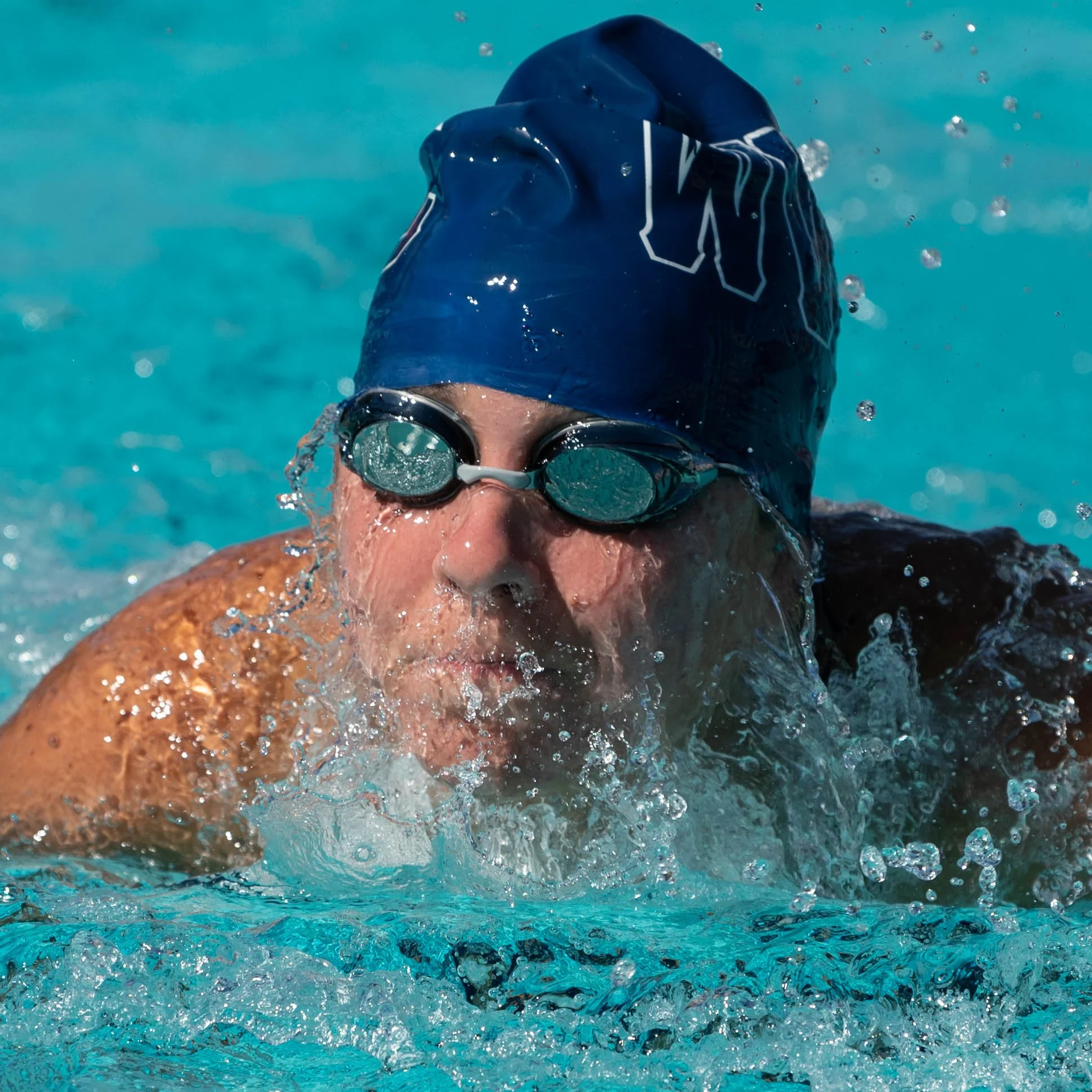 Swimmer in a pool wearing a blue swim cap and goggles