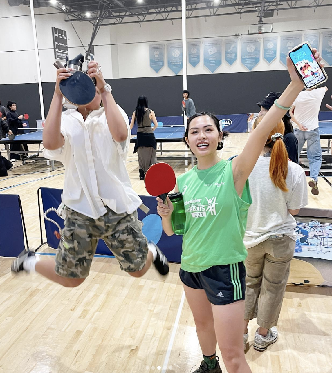 Two people in front of table tennis tables