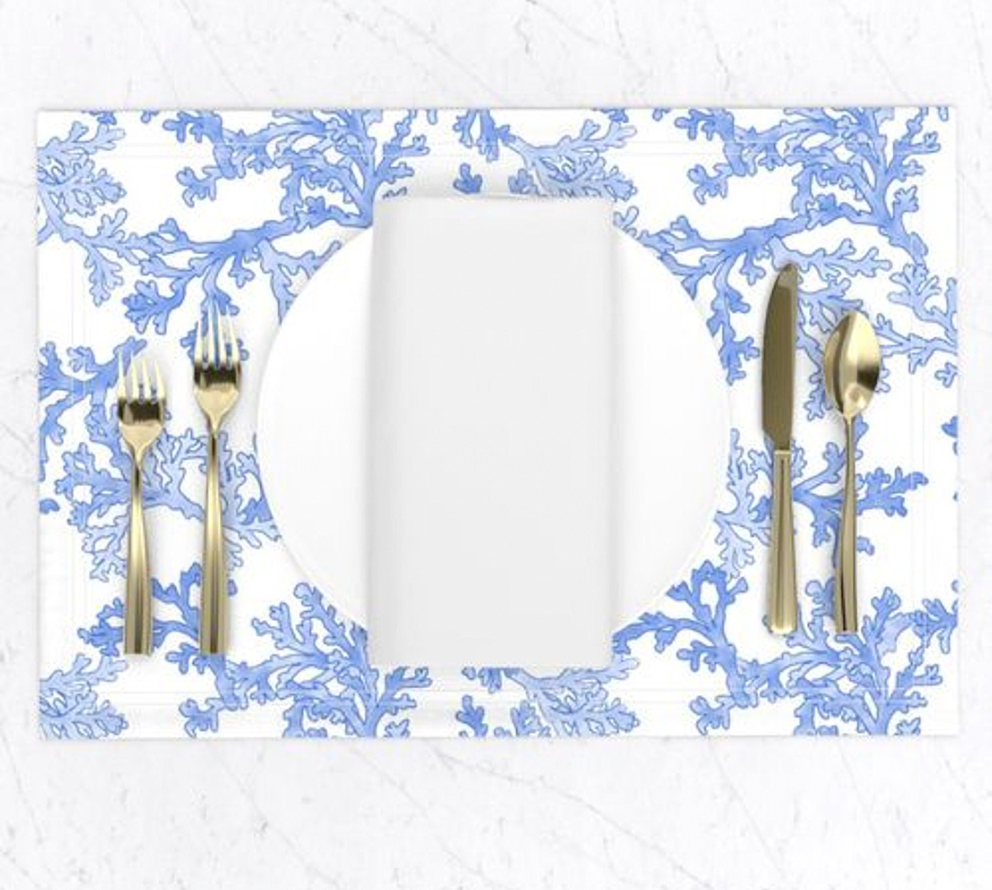 Place setting with a white plate on a cloth placemat featuring a blue and white coastal pattern