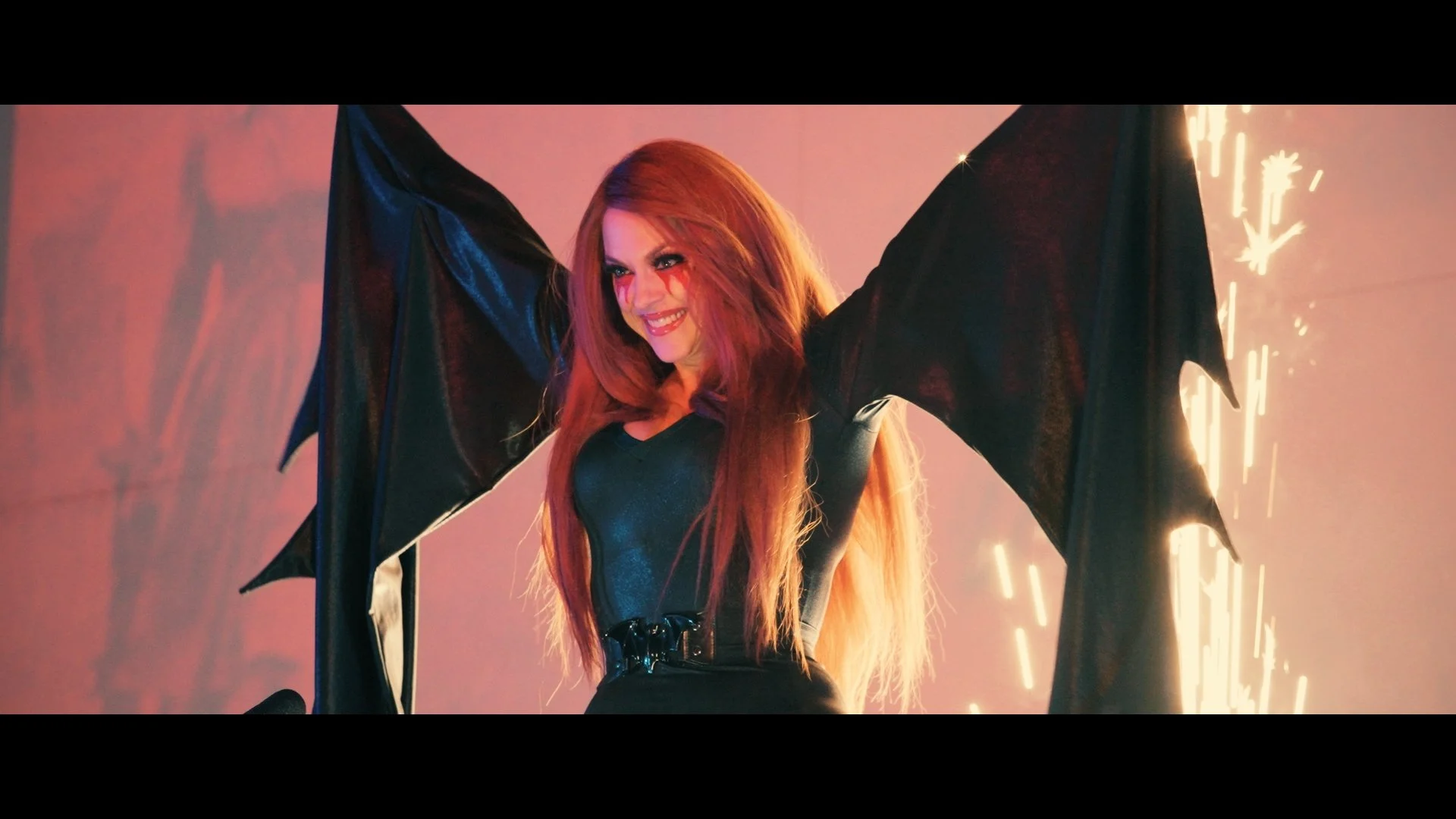 Scarah with bat-like black wings, smiling as sparks fly behind her