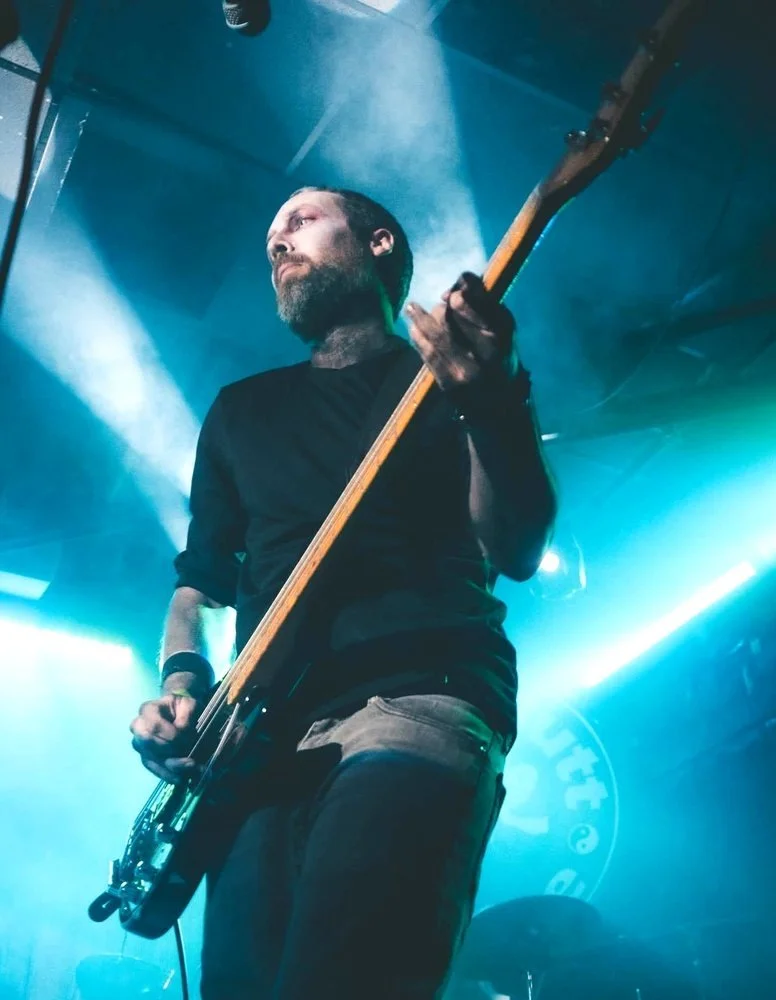 Count Bockula playing bass under teal stage lights and haze
