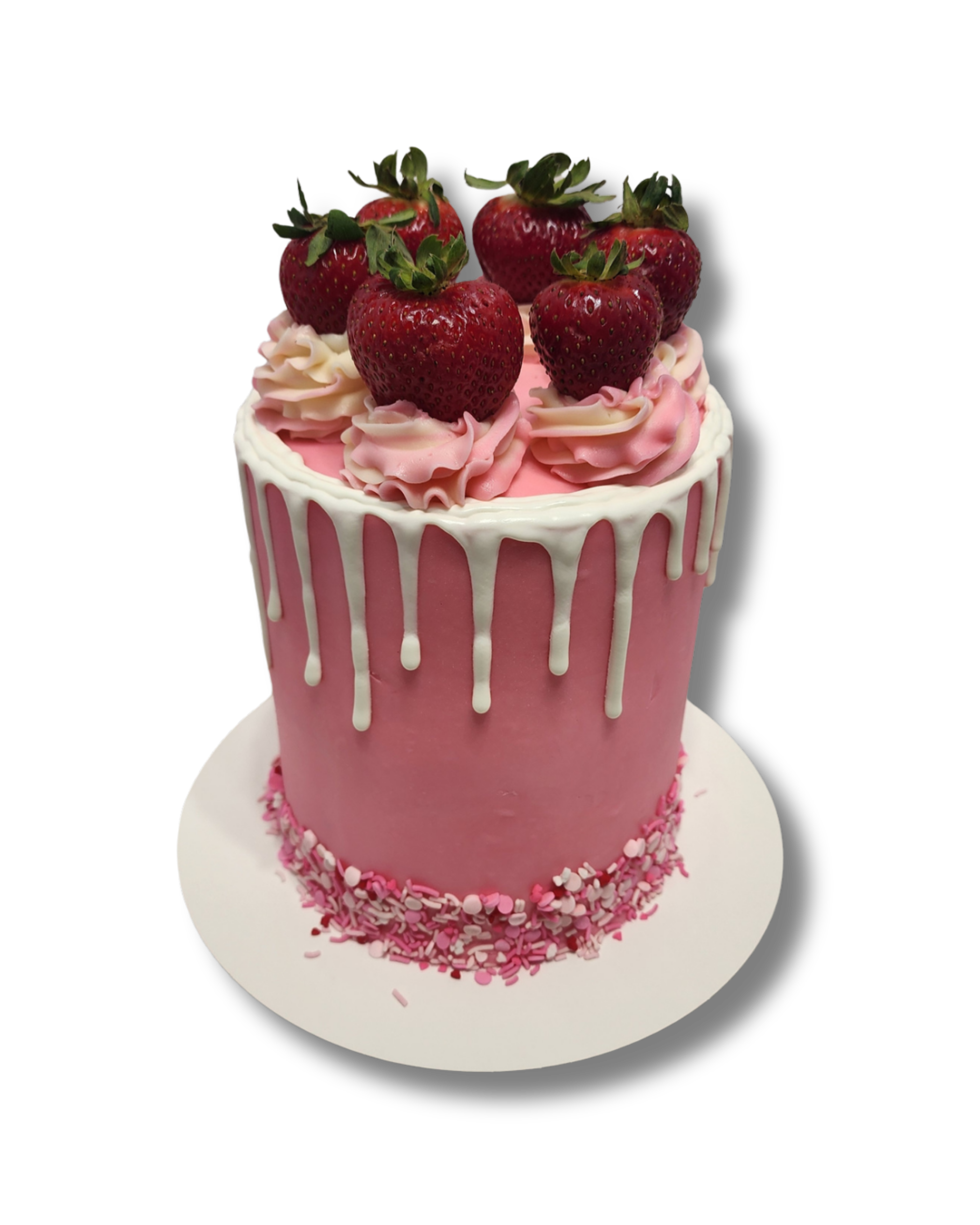 Pink cake with white drip icing, topped with strawberries and pink and white decorative frosting, on a white cake board.