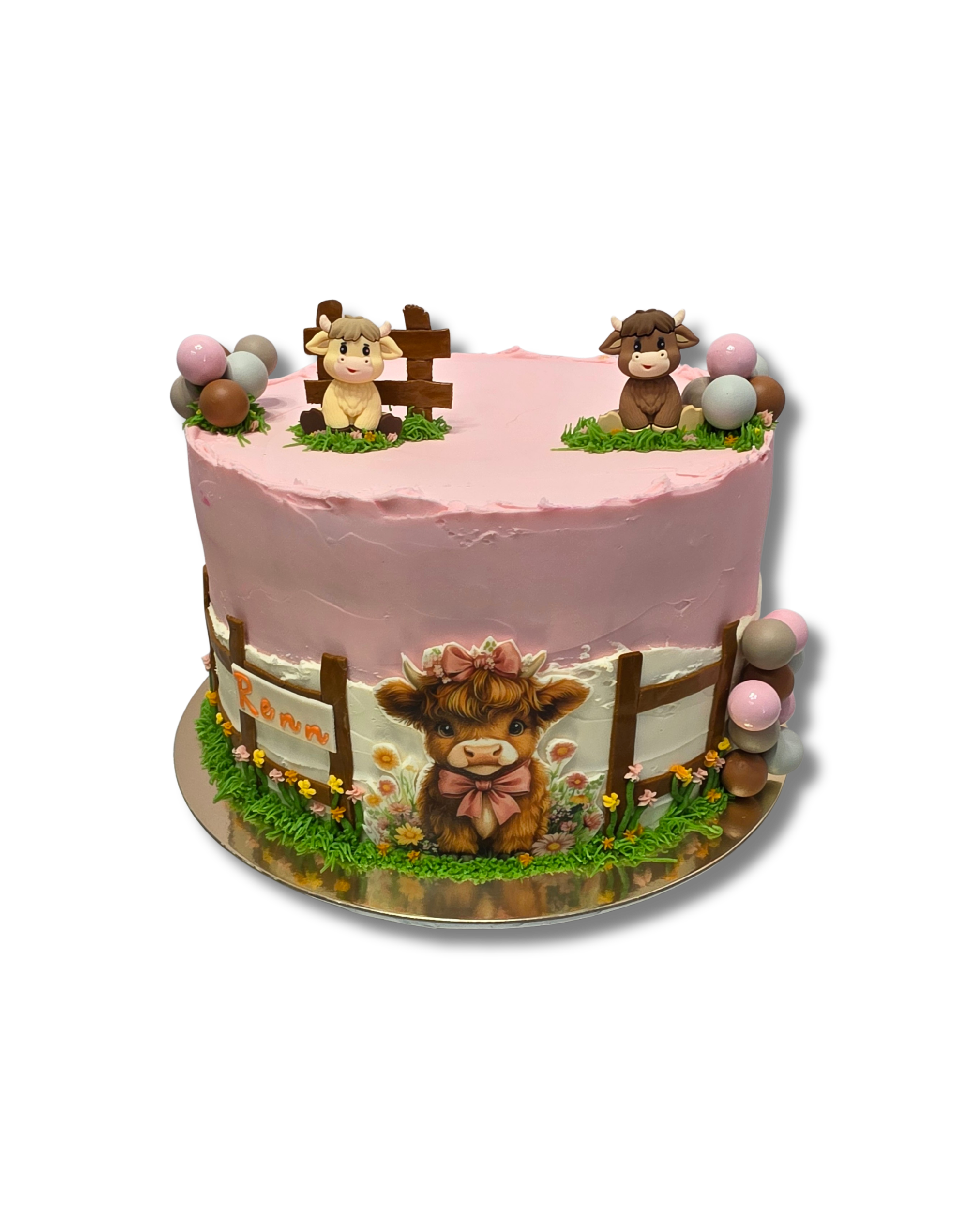 A pink decorated birthday cake with farm animal themed figurines, including cows, and a dog illustration on the side.