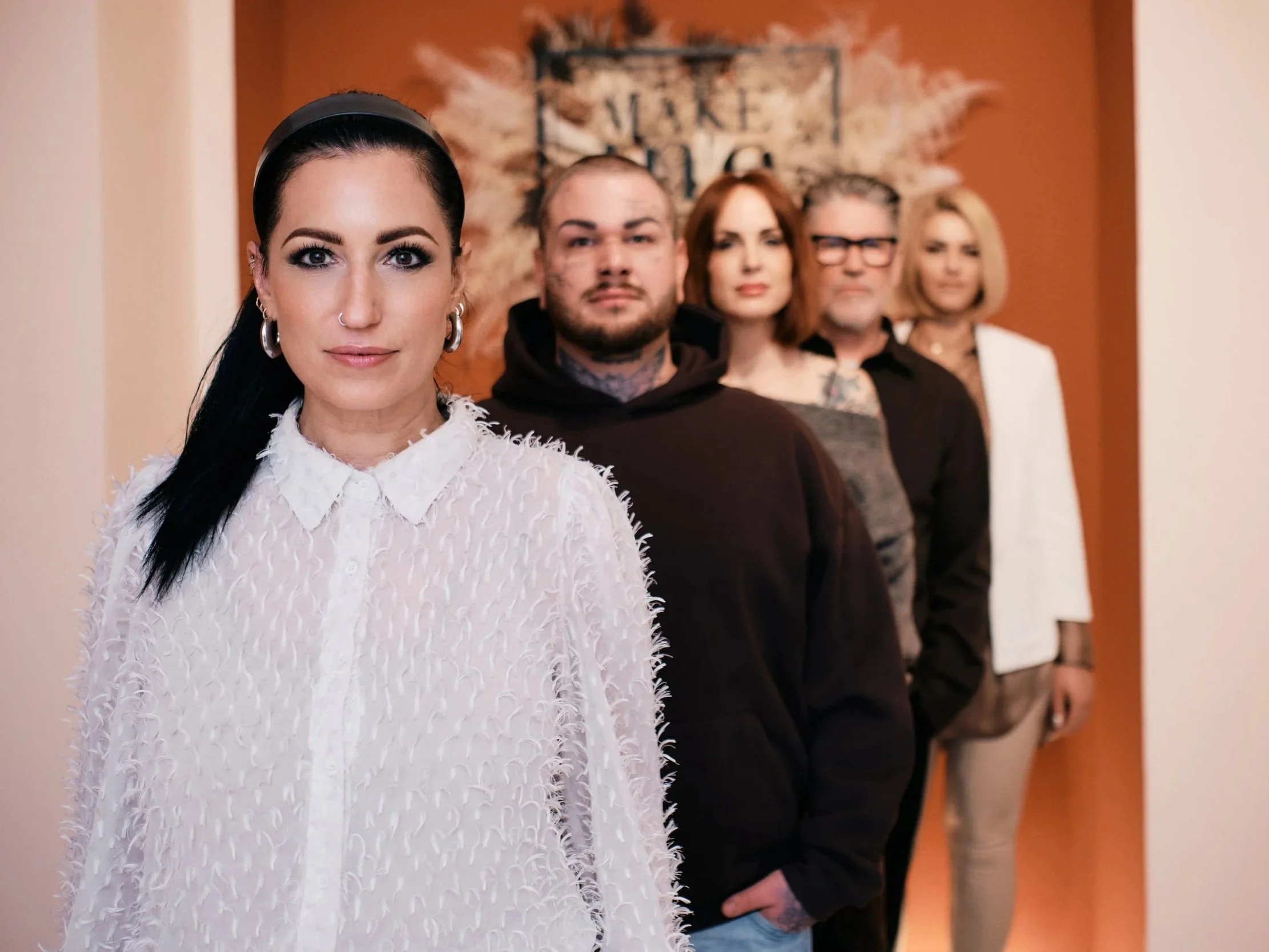 Fünf Menschen stehen in einer Reihe vor einem Wandbild mit dem Text "Make a life,".