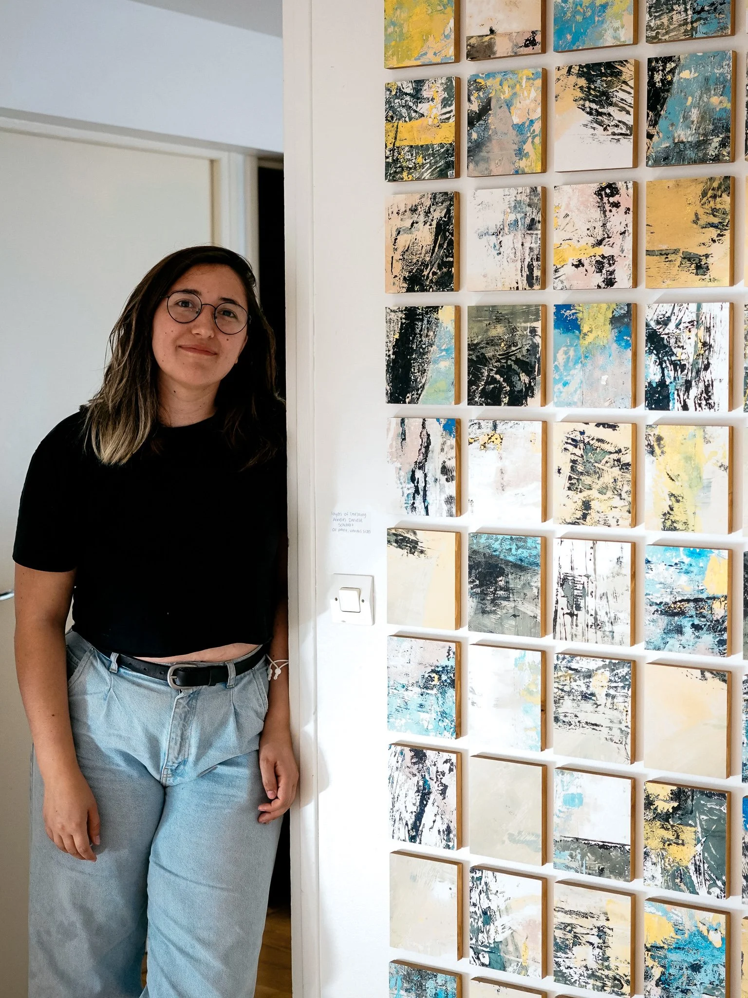 Artist posing next to installed artwork Early Recollections — An oil paint monotype mounted on oak wood