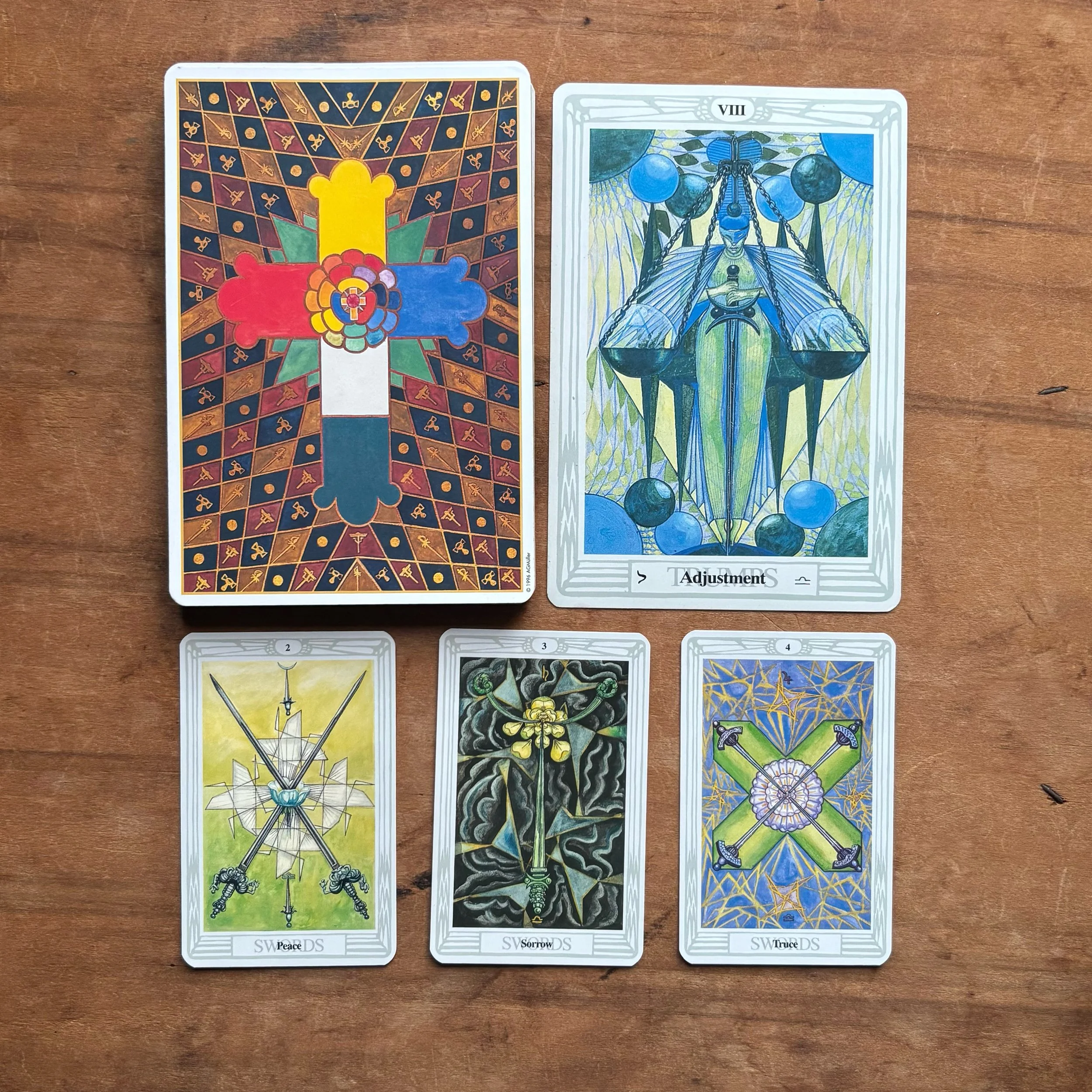 Justice and Adjustment cards from the Thoth Tarot are pictured with their associated Minor Arcana cards, the two, three, and four of Swords.