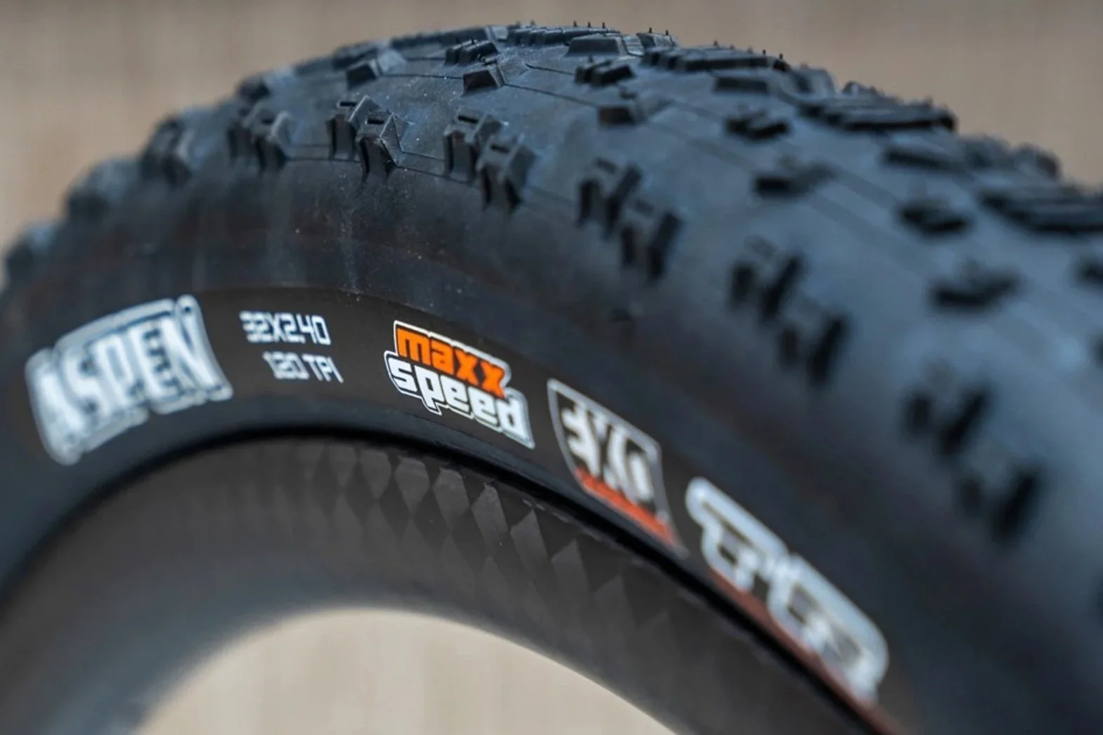 Close-up image of a bicycle tire with black rubber tread and branding stickers showing specifications.