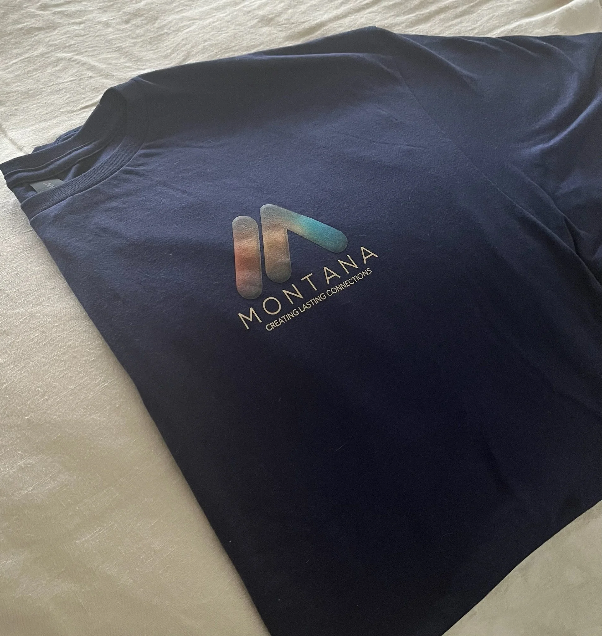 Montana Creatives navy t-shirt on a bed