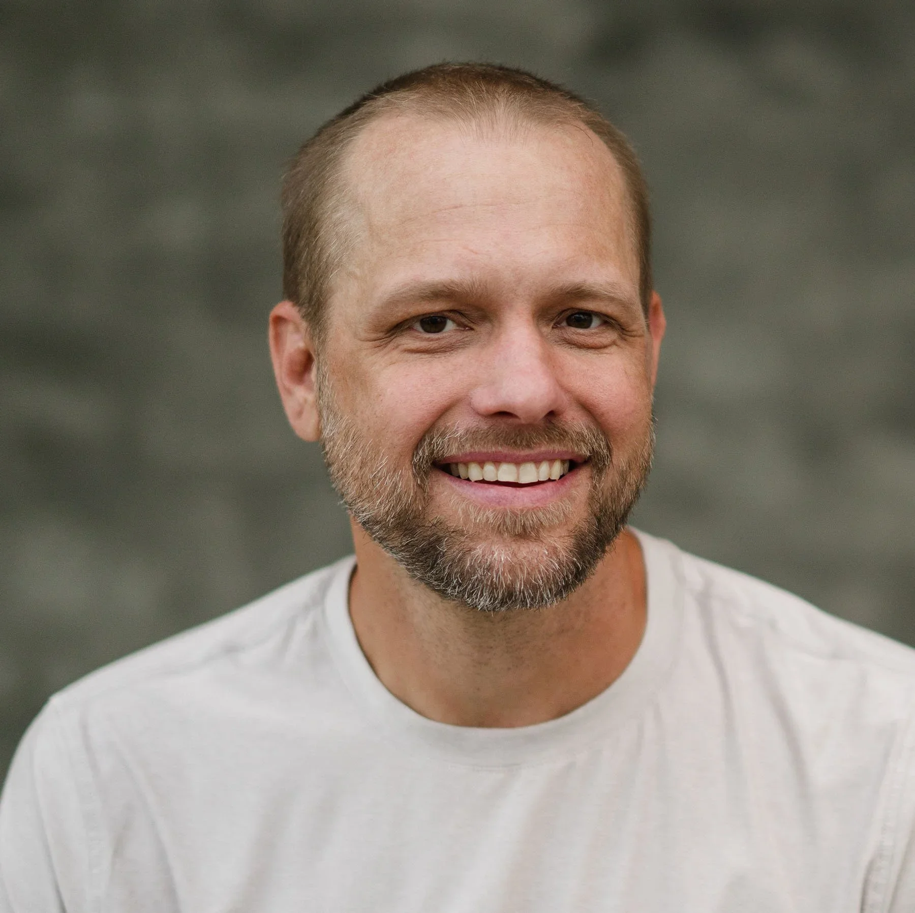 Kevin Schrage smiling in a head and shoulders portrait against a neutral background.
