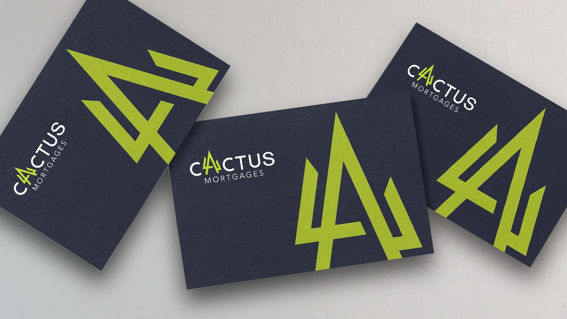 Business cards for Cactus Mortgages on a light gray surface, featuring a navy blue background, a green cactus logo, and white and green text.