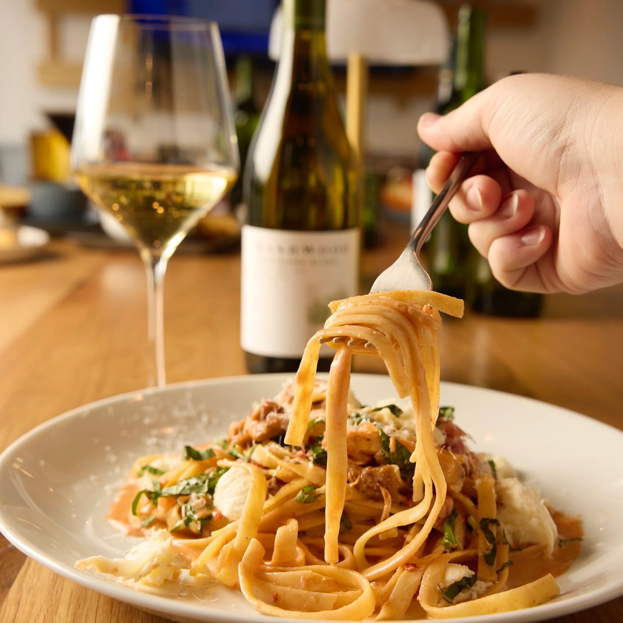 Fork-twirled creamy pasta with parmesan and fresh herbs at Liberty Tavern in Polaris, Columbus, Ohio, served with a glass of white wine.