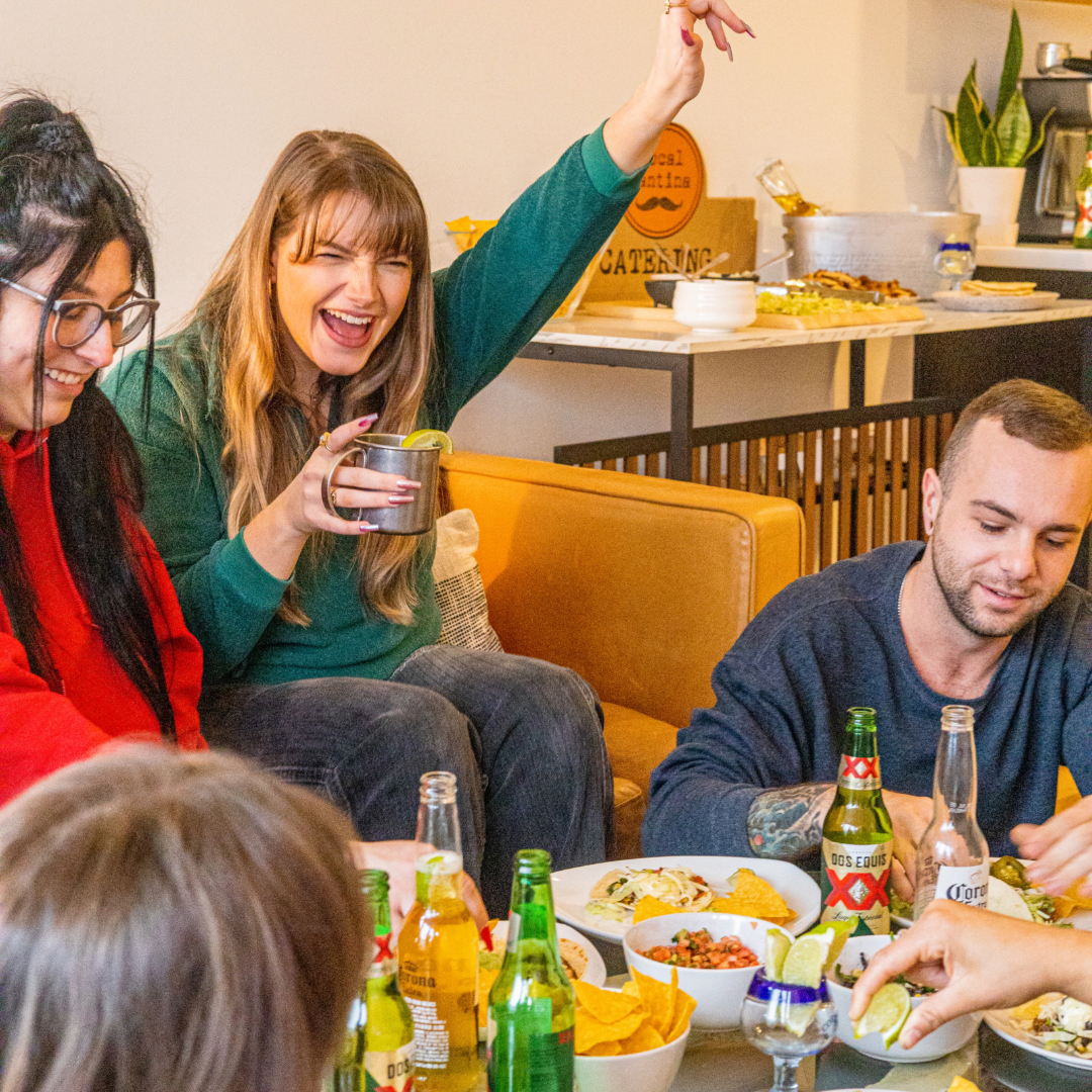 Friends gathered around a table enjoying food and drinks together in a casual restaurant setting during a celebration.