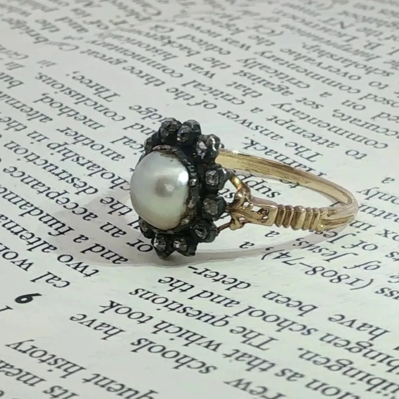 Antique Georgian 15k Pearl Old Mine Cut Diamond Ring Side View on book paper