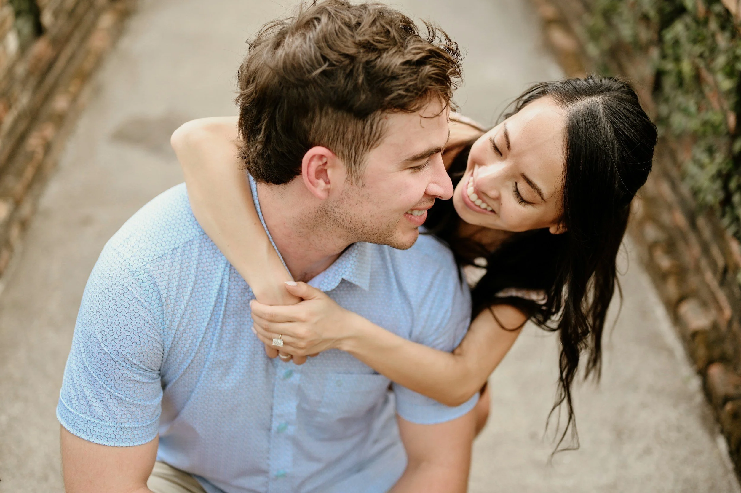 A couple sharing a joyful moment outdoors, with the woman giving the man a piggyback ride, both smiling and laughing.