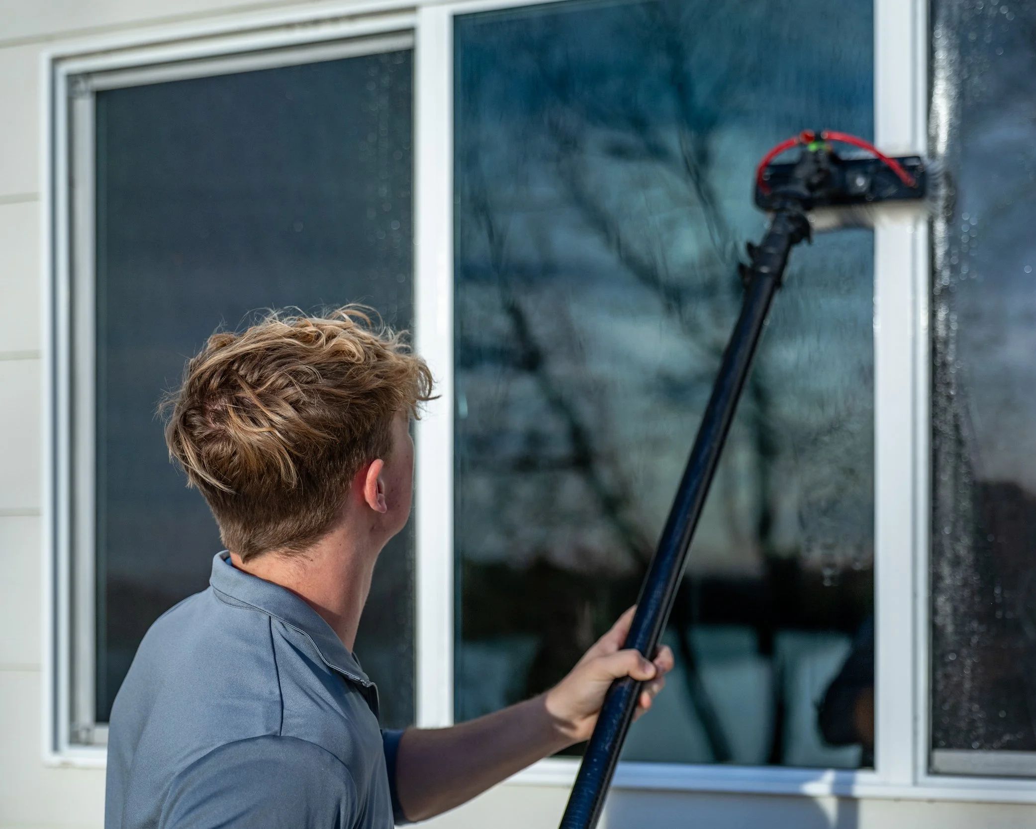 A person cleaning a window with a power washer.