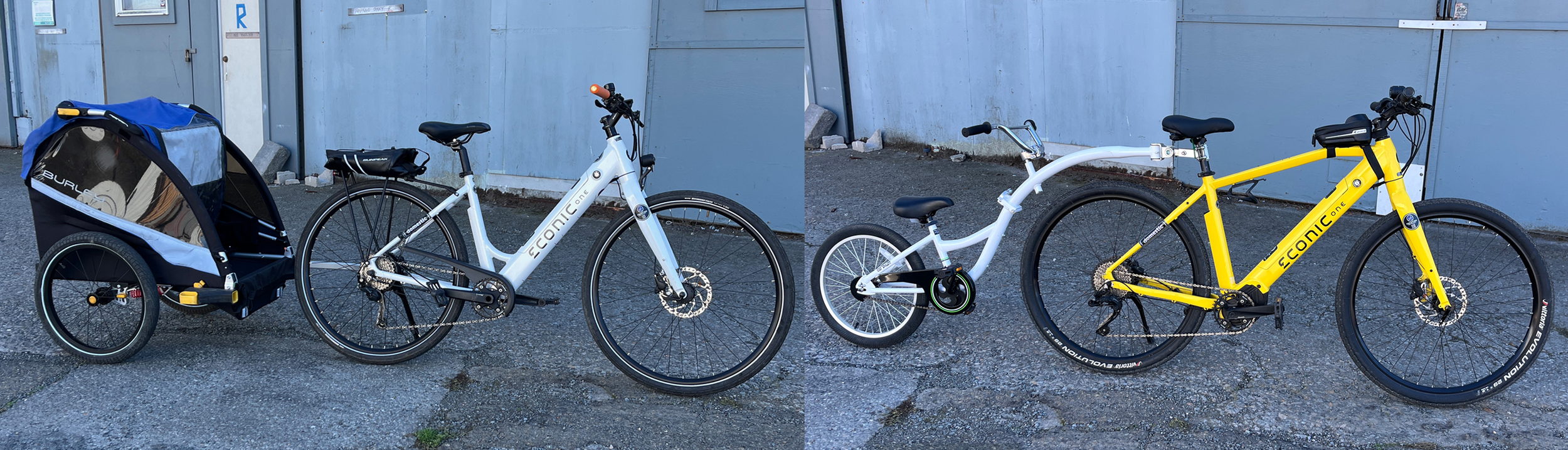 Two bikes with a bike trailer parked outside next to a blue wall. The left bike is white with a bike trailer attached, and the right bike is yellow.
