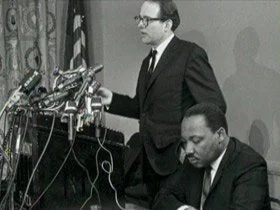 in a black and white photo, Rev. William Sloan Coffin stands behind a lectern and to his left is Rev. Martin Luther King, Jr.