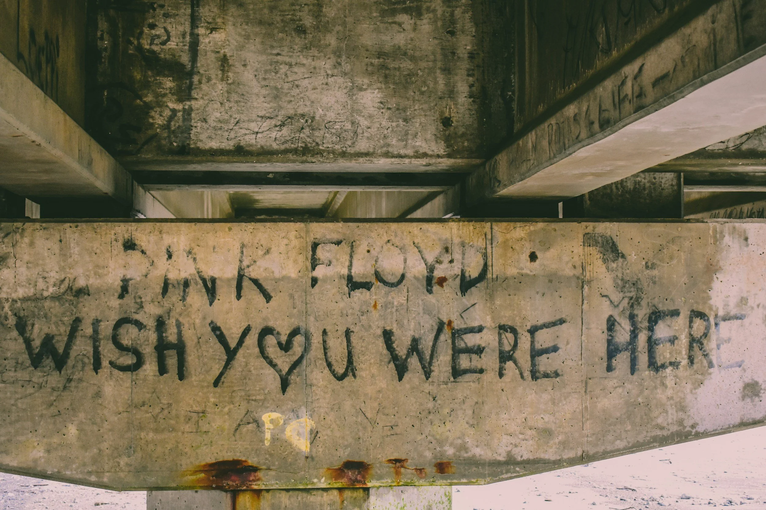 Graffitti under a bridge has the words "Pink Floyd Wish You Were Here" spray painted on concrete.