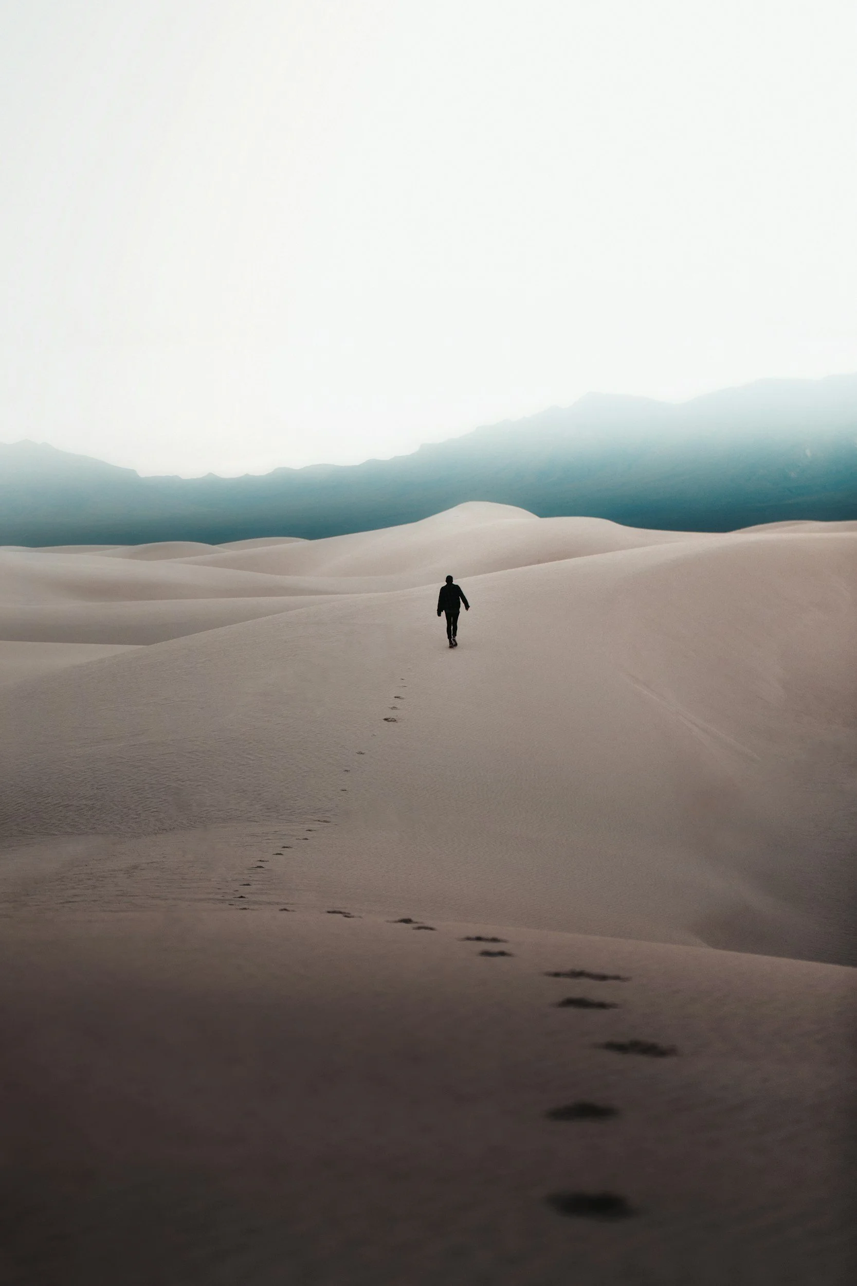 A solitary figure is in the distance, leaving a trail of footprints behind.