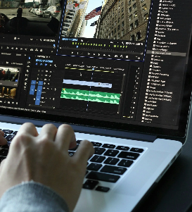 Persona editando un video en una computadora portátil con múltiples pantallas de edición de video.